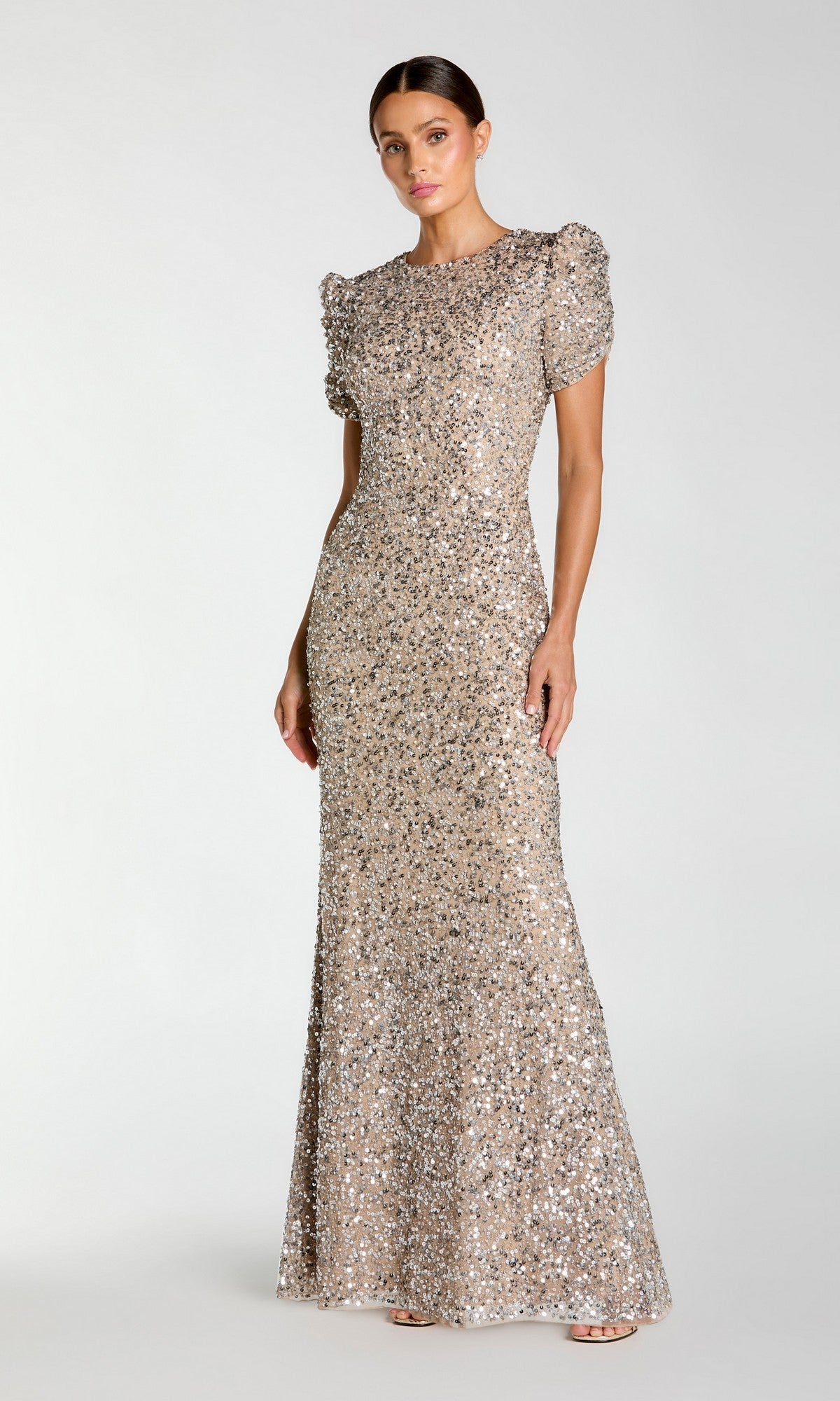 Woman modeling the Mac Duggal 24003 Short Sleeve Sequin Formal Dress, a fitted, floor-length gown with puff sleeves, against a plain light background.